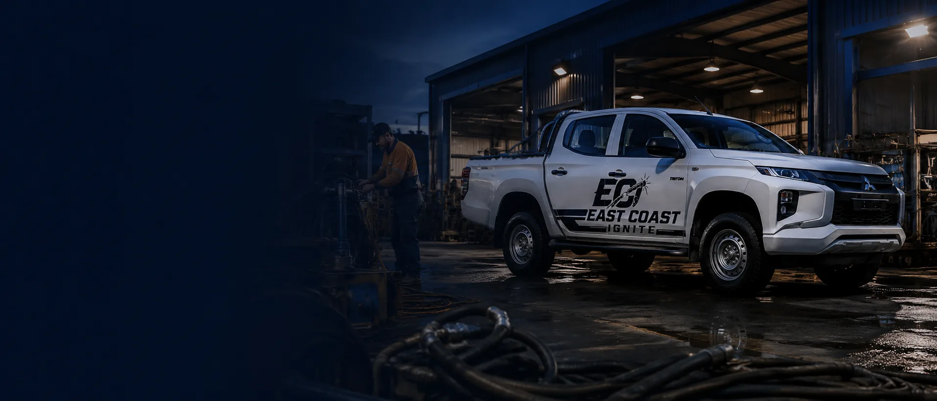 East Coast Ignite branded service vehicle parked at a workshop in the evening, with a technician working on equipment in the background